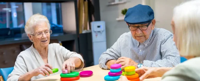 Seniors engaged in memory care activities playing skill games together at a table in nursing home