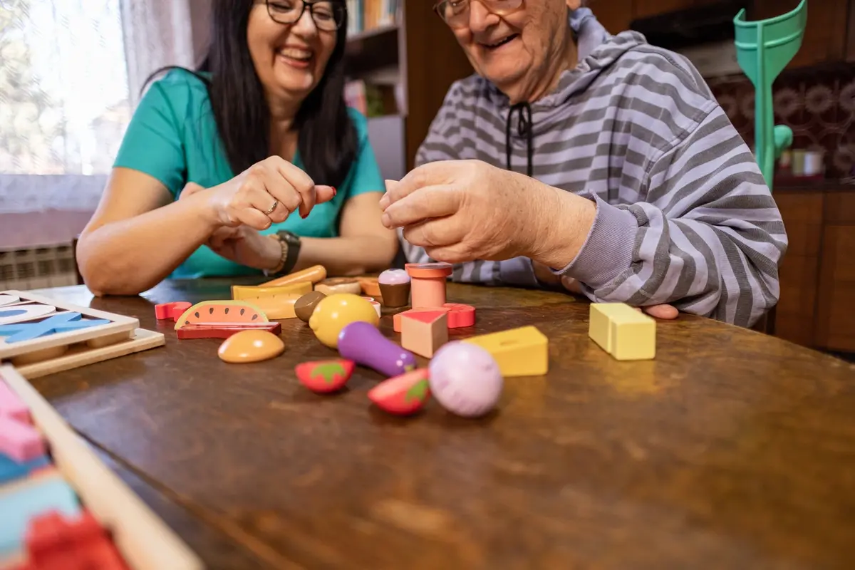 Brain Exercises for Seniors: caregiver and older adult play memory game with colorful pieces