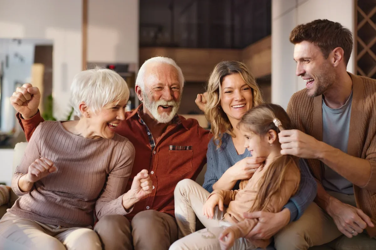 How to Pay for Memory Care as a Family Cheerful extended family spending time together in a living room while discussing how to pay for memory care.